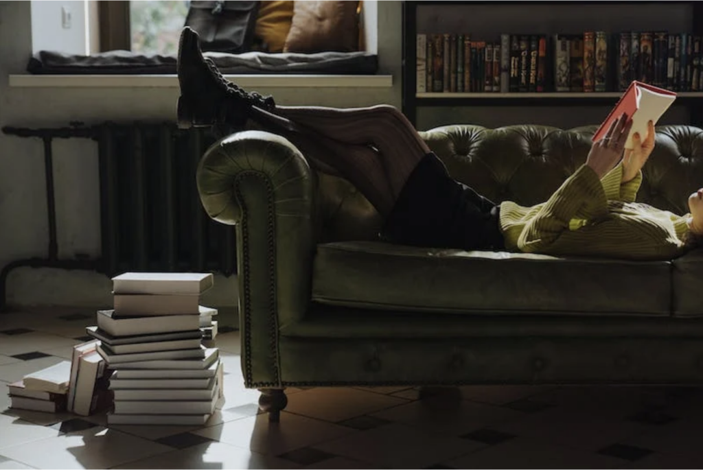woman lying on a couch while reading a book