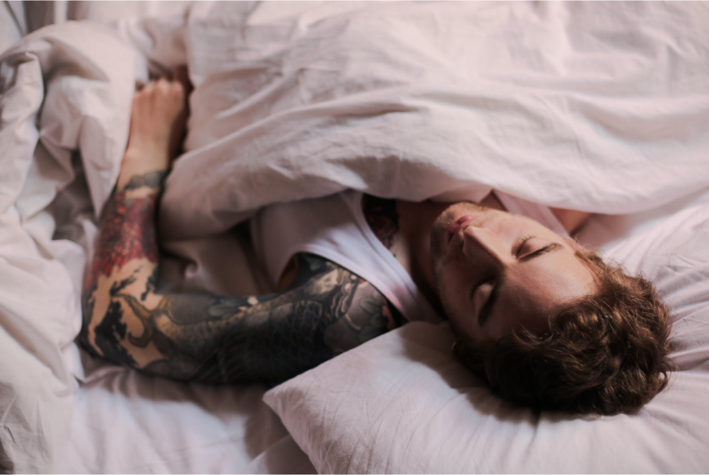 man with tattoo sleeping on bed