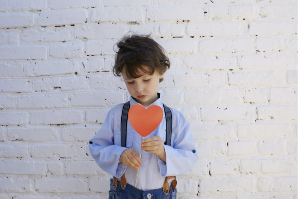 boy holding a heart-shaped paper on stick