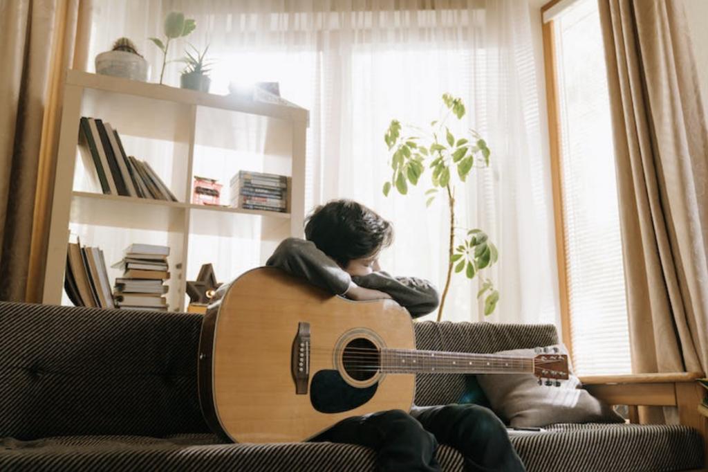 Man holding acoustic guitar on couch