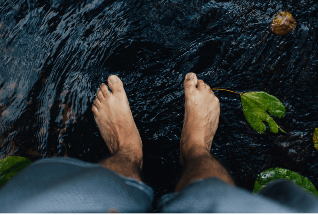 a man's feet on a river