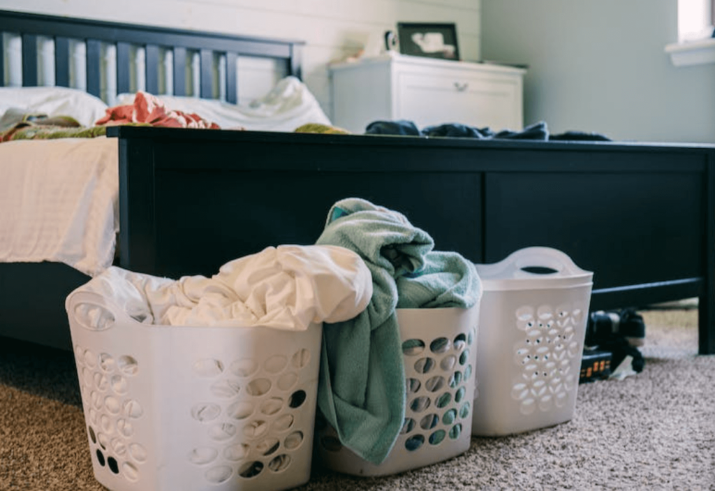 laundry baskets filled with clothes beside a bed