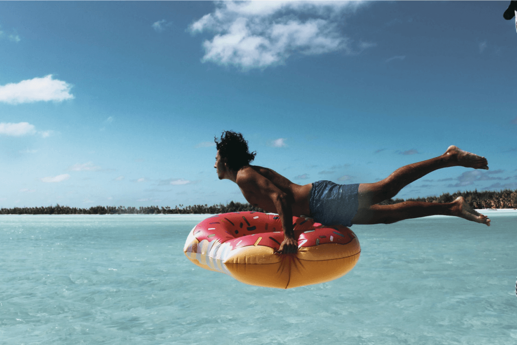 Man jumping to the ocean with a donut floater